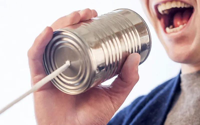 Person talking through a can attached to a piece of string